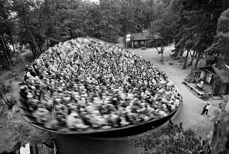 Mustavalkoinen kuva, jossa yleisö pyörii liikkuvassa katsomossa hieman sumeina.